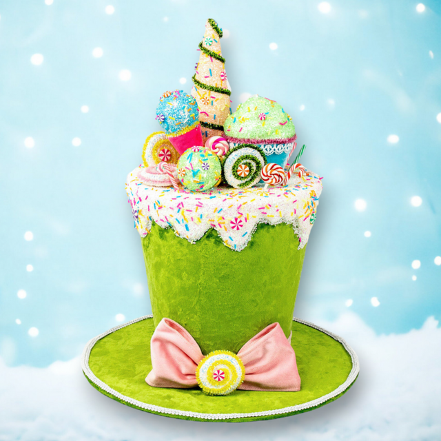 Green velvet candy hat tree topper piled with faux candy and cupcakes, with a pink bow.