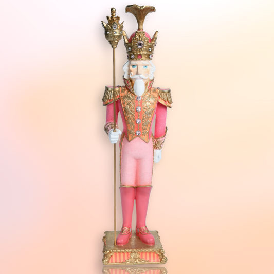 Pink and gold nutcracker figurine holding a staff.