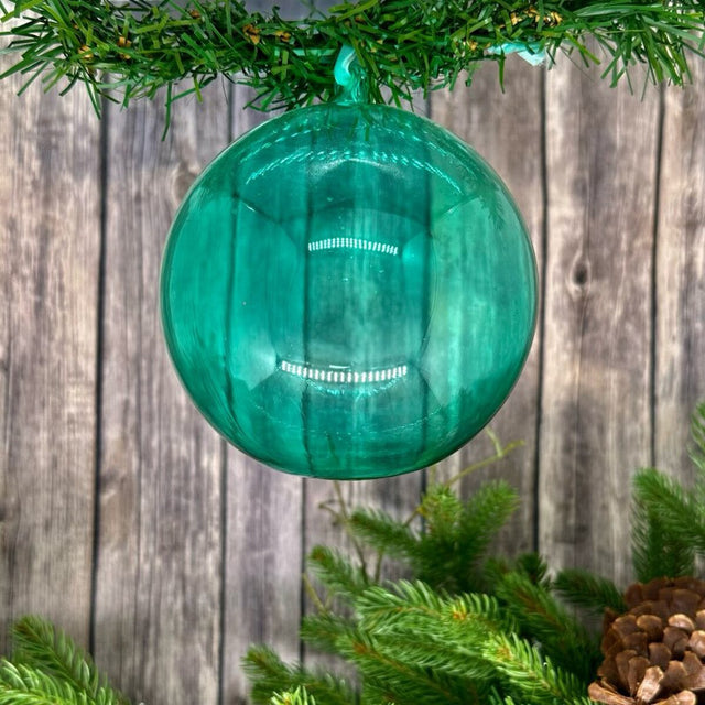 Clear glass ball ornament with a soft celadon glow.