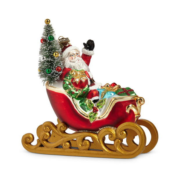 Red glass Santa sleigh ornament with gold runners, a miniature tree and wrapped gifts.