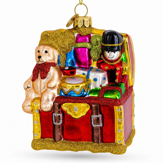 Red glass toy trunk ornament with a teddy bear, toy soldier and drum spilling out.