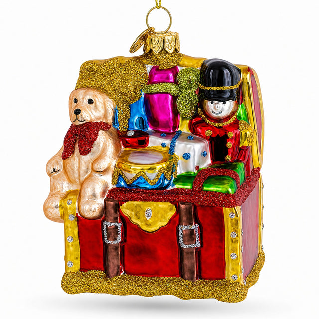 Red glass toy trunk ornament with a teddy bear, toy soldier and drum spilling out.