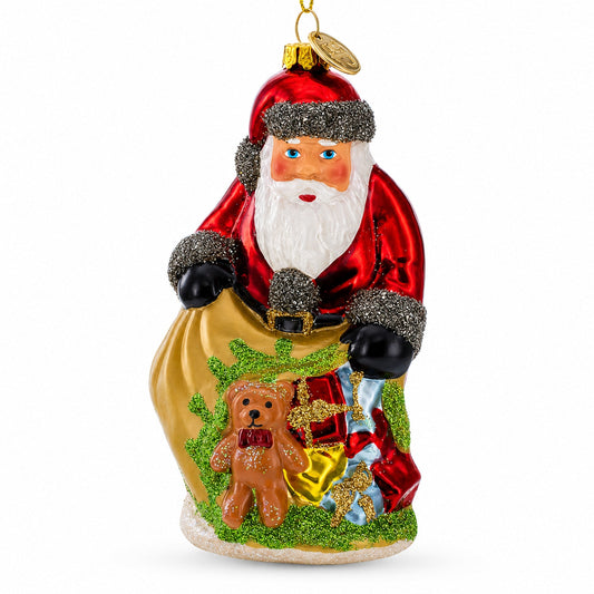 Red glass Santa ornament holding a gold sack with a teddy bear and gifts.